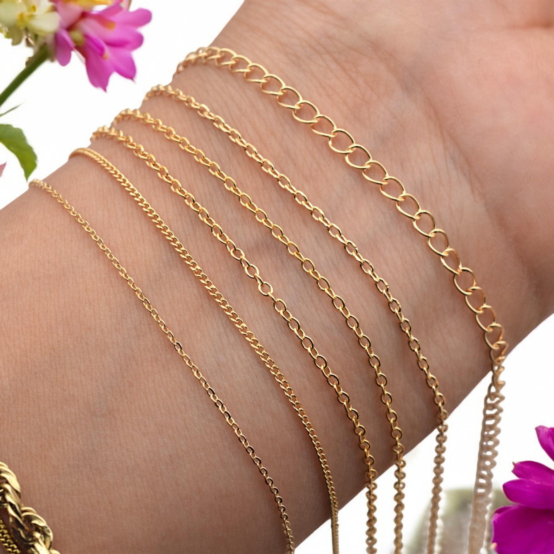 Close-up of wrist with five gold filled cable link chains labeled by width and style