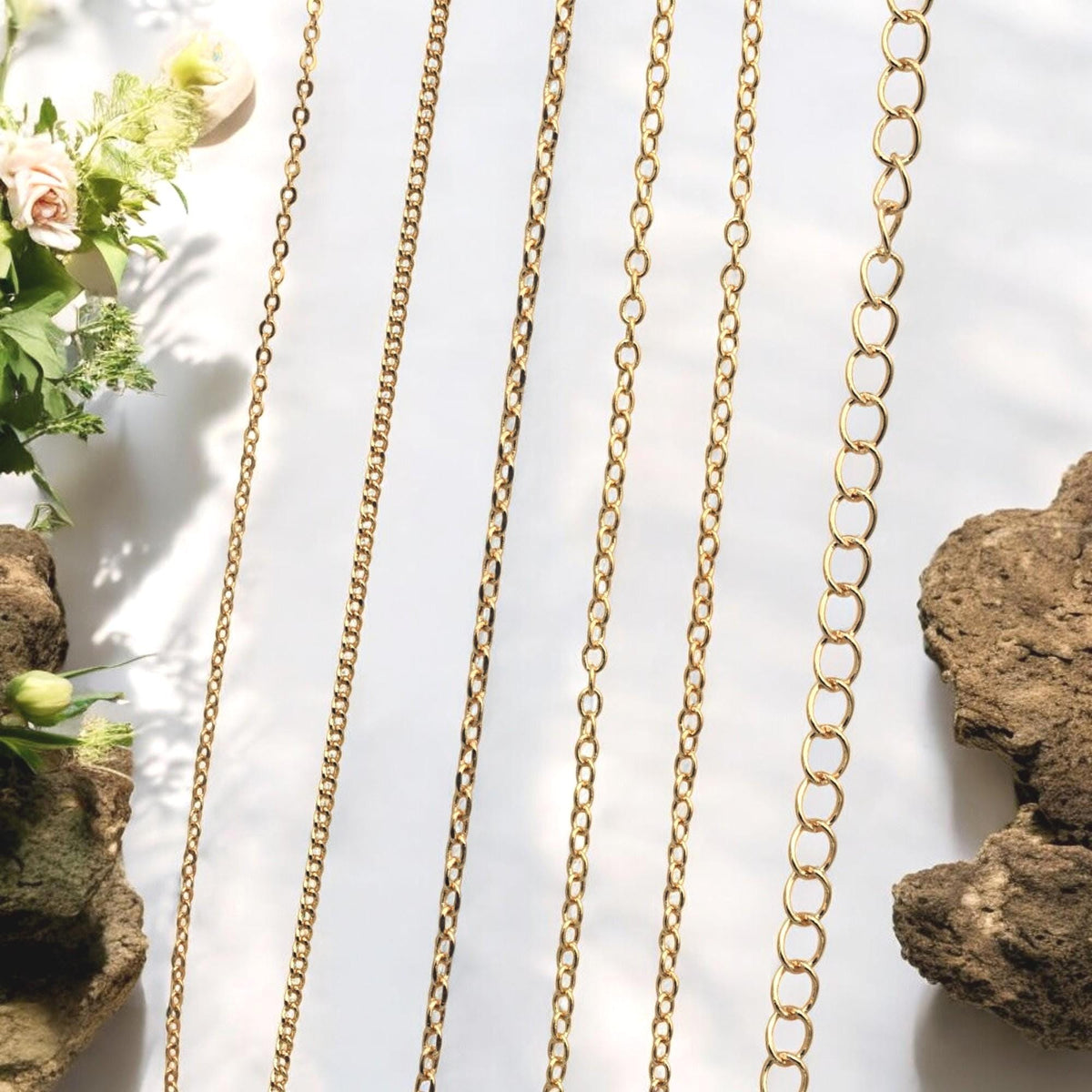 Flat and oval cable link chains in 18K gold finish shown on wrist for comparison