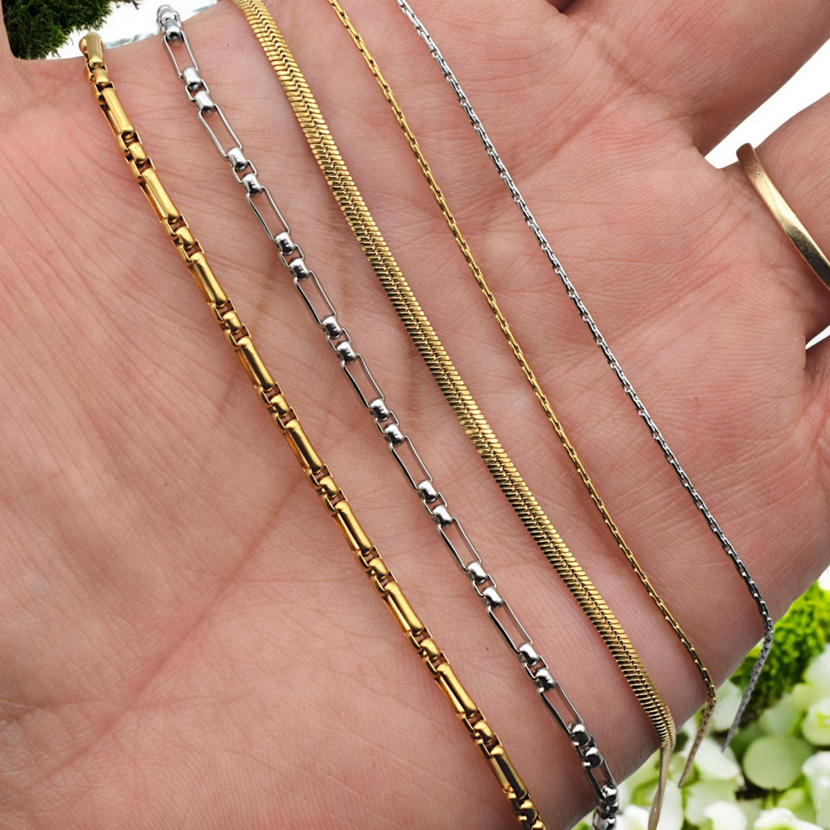 Close-up of stainless steel box chain in gold and silver tones, sold by yard for jewelry making.