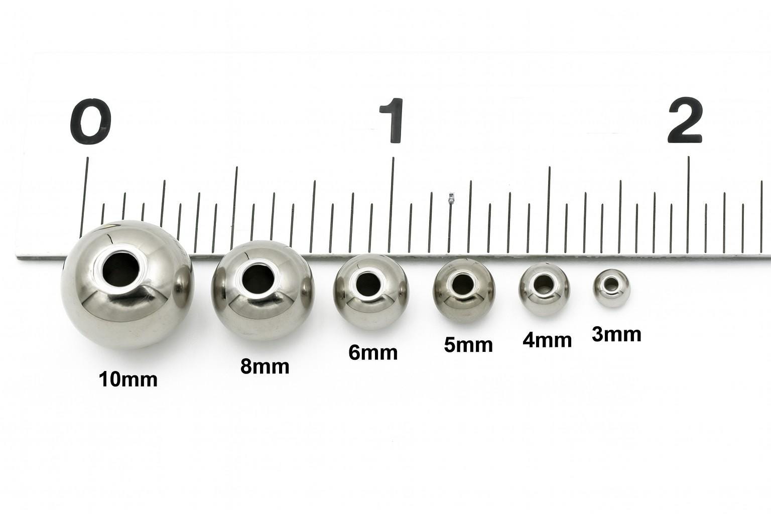 Close-up of shiny stainless steel round spacer beads in assorted sizes on a white background