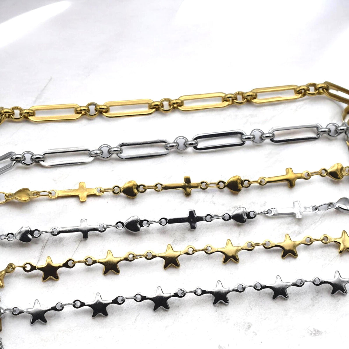 Charm chain with star, heart, and cross connectors laid flat on white background for jewelry making.