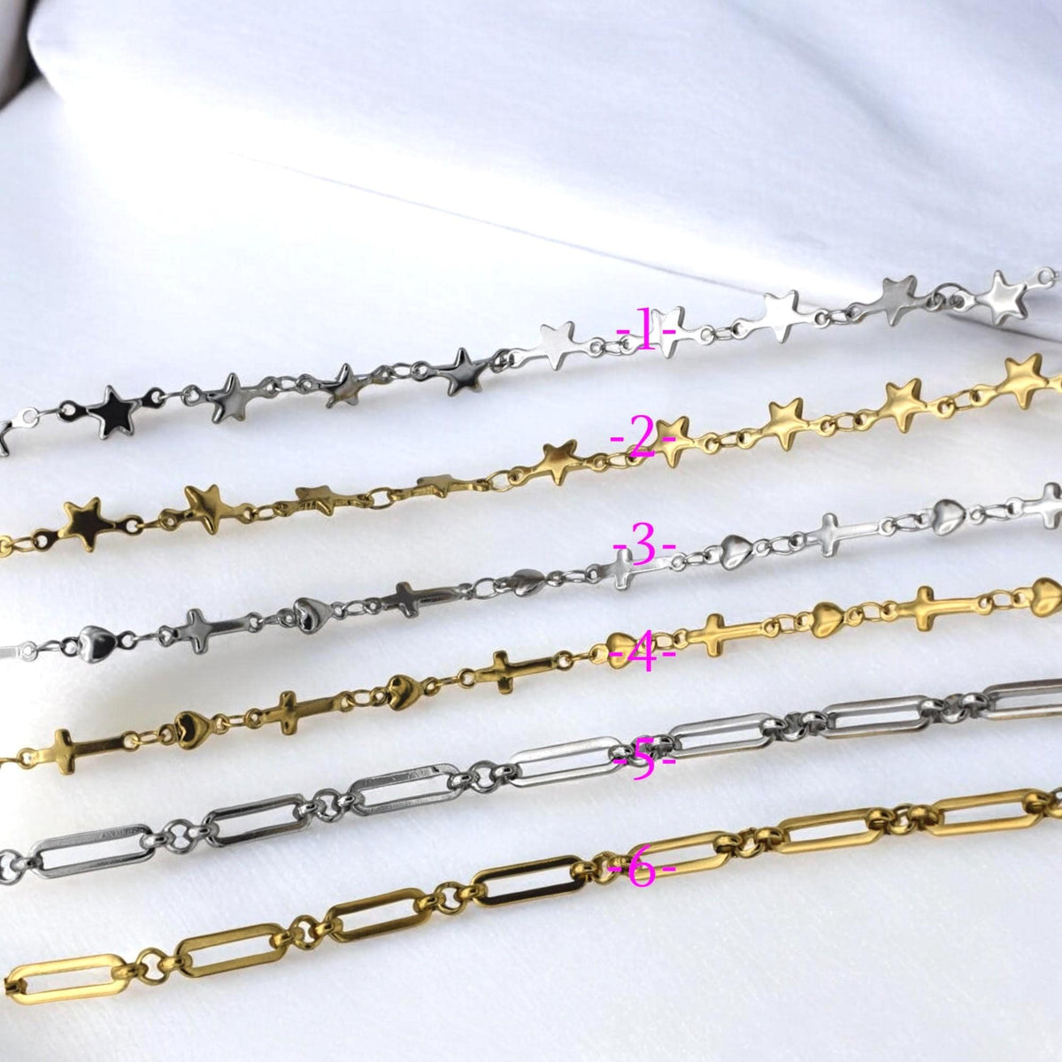 Flat lay of star, heart, and cross link chains in gold and silver for jewelry supplies.