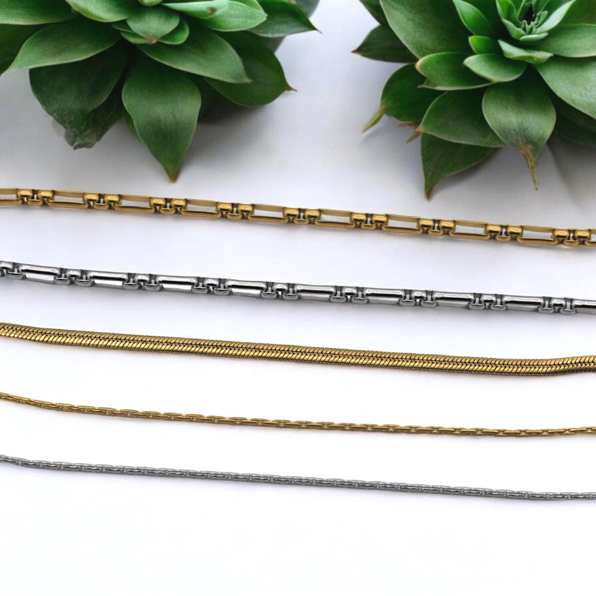 Paperclip style stainless steel chain in polished gold tone, shown coiled for wholesale supply.