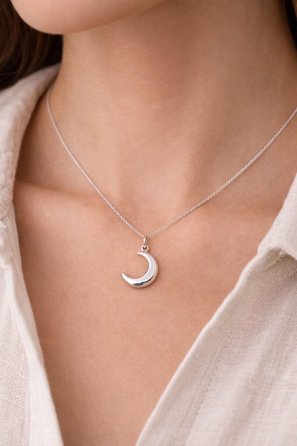 Silver‑tone crescent moon charm with smooth, reflective surface.
Charm de luna plateada con superficie suave y reflectante.