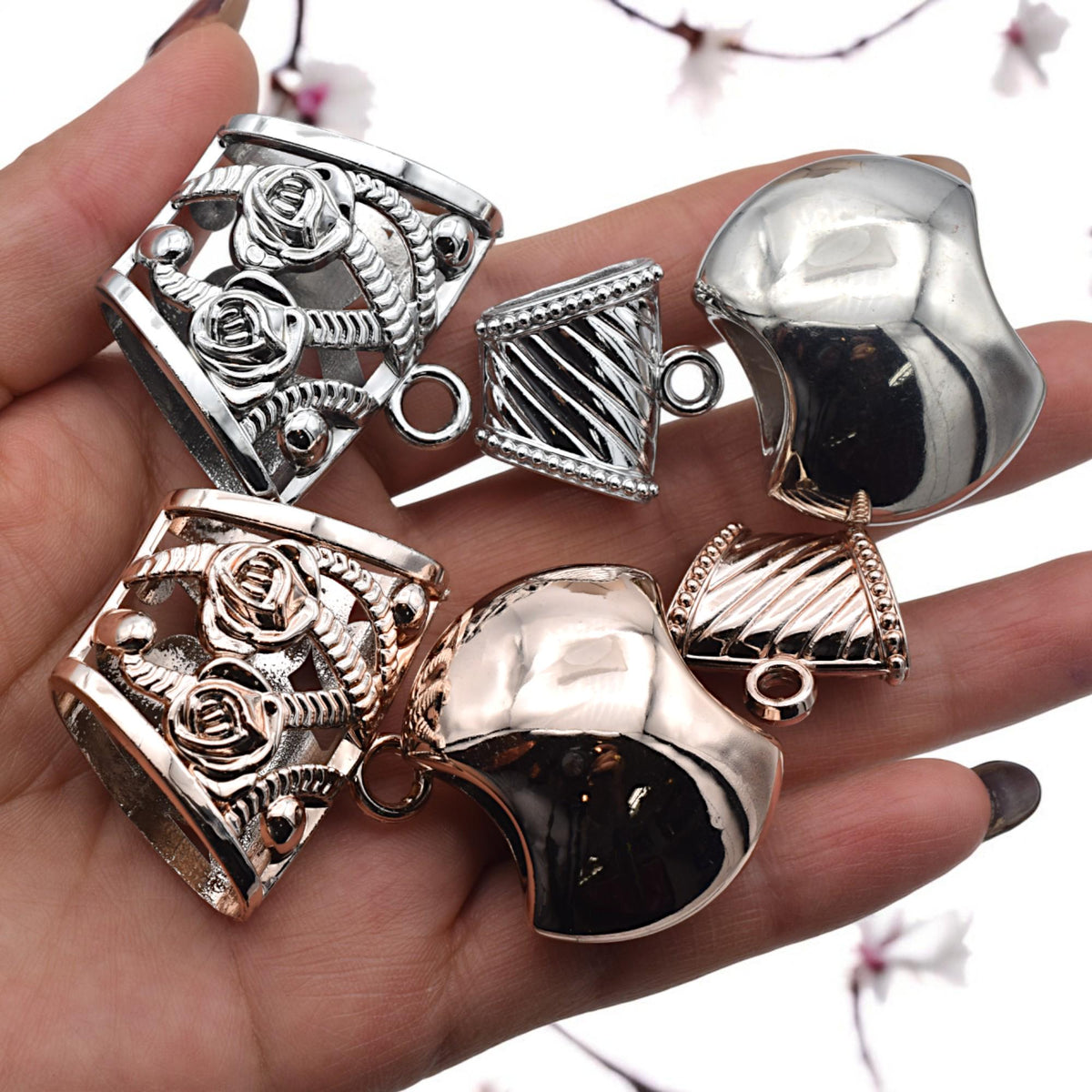 Set of 25 mixed-metal loop bail beads arranged neatly for product display.
Paquete de 25 cuentas con asa en tonos mixtos organizadas para exhibición.