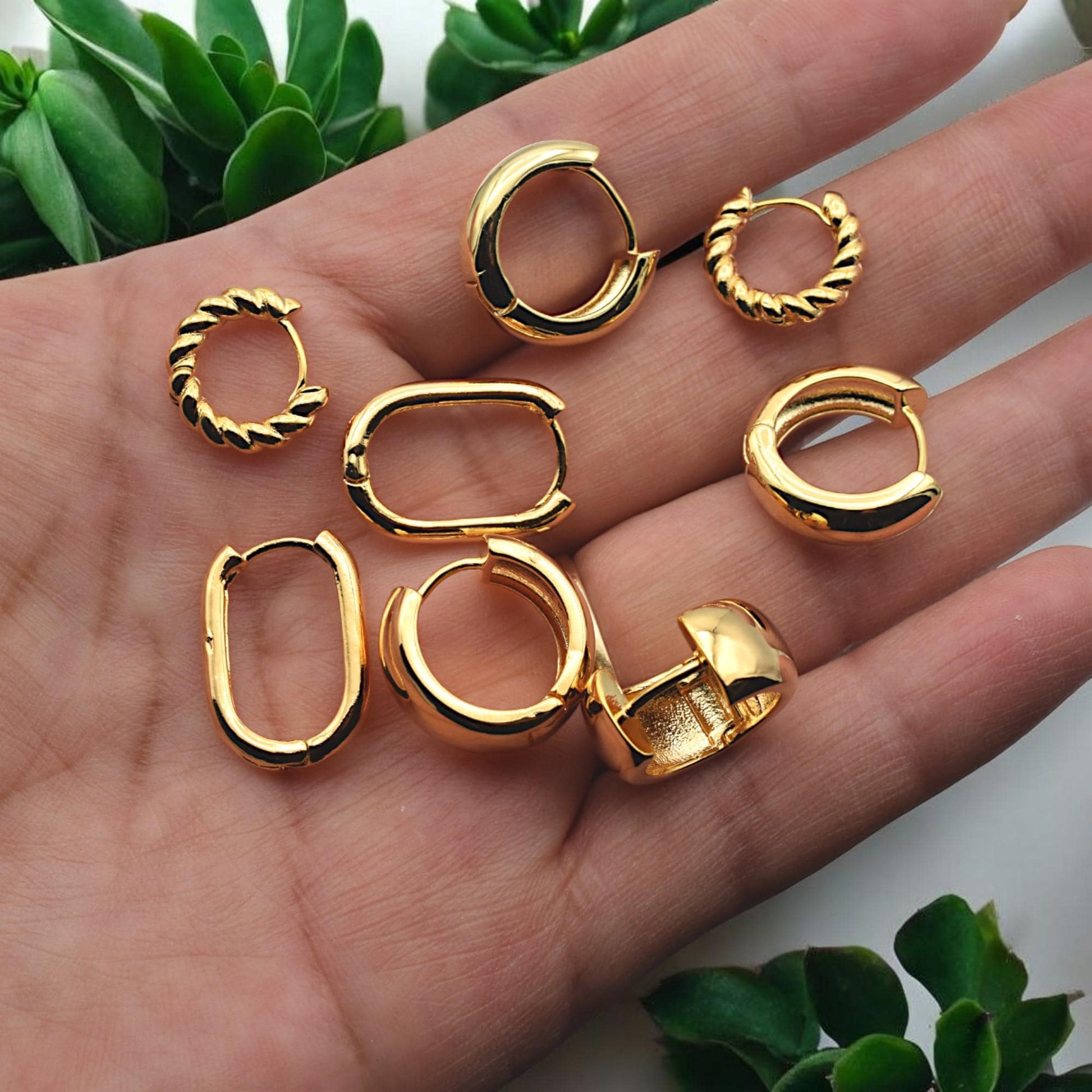 A hand holding the different hoop earring styles to provide a clear sense of scale and real-world sizing.