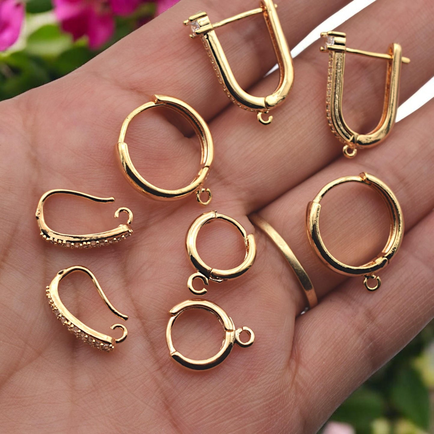 A hand holding the various gold hoop styles to demonstrate the relative size and "real-life" scale of the findings.