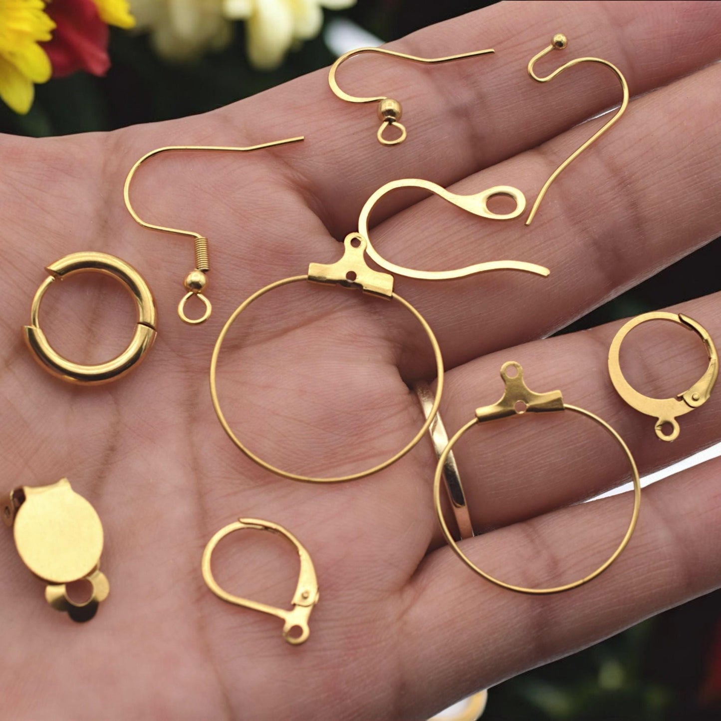 Gold stainless steel lever back earring findings arranged neatly on white surface.
Bases de aretes tipo lever back en acero inoxidable dorado sobre fondo blanco.
