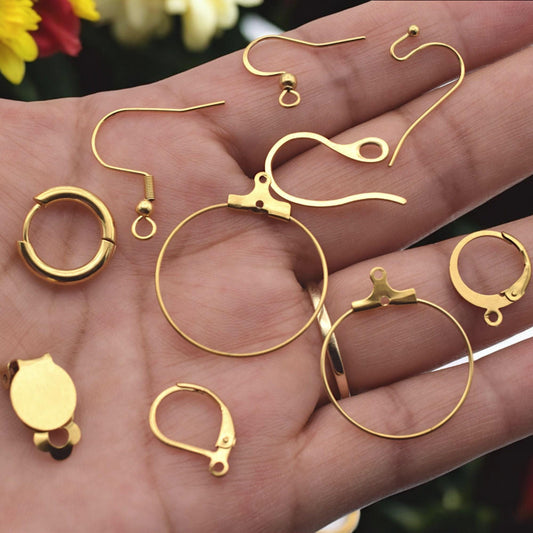 Gold stainless steel lever back earring findings arranged neatly on white surface.
Bases de aretes tipo lever back en acero inoxidable dorado sobre fondo blanco.