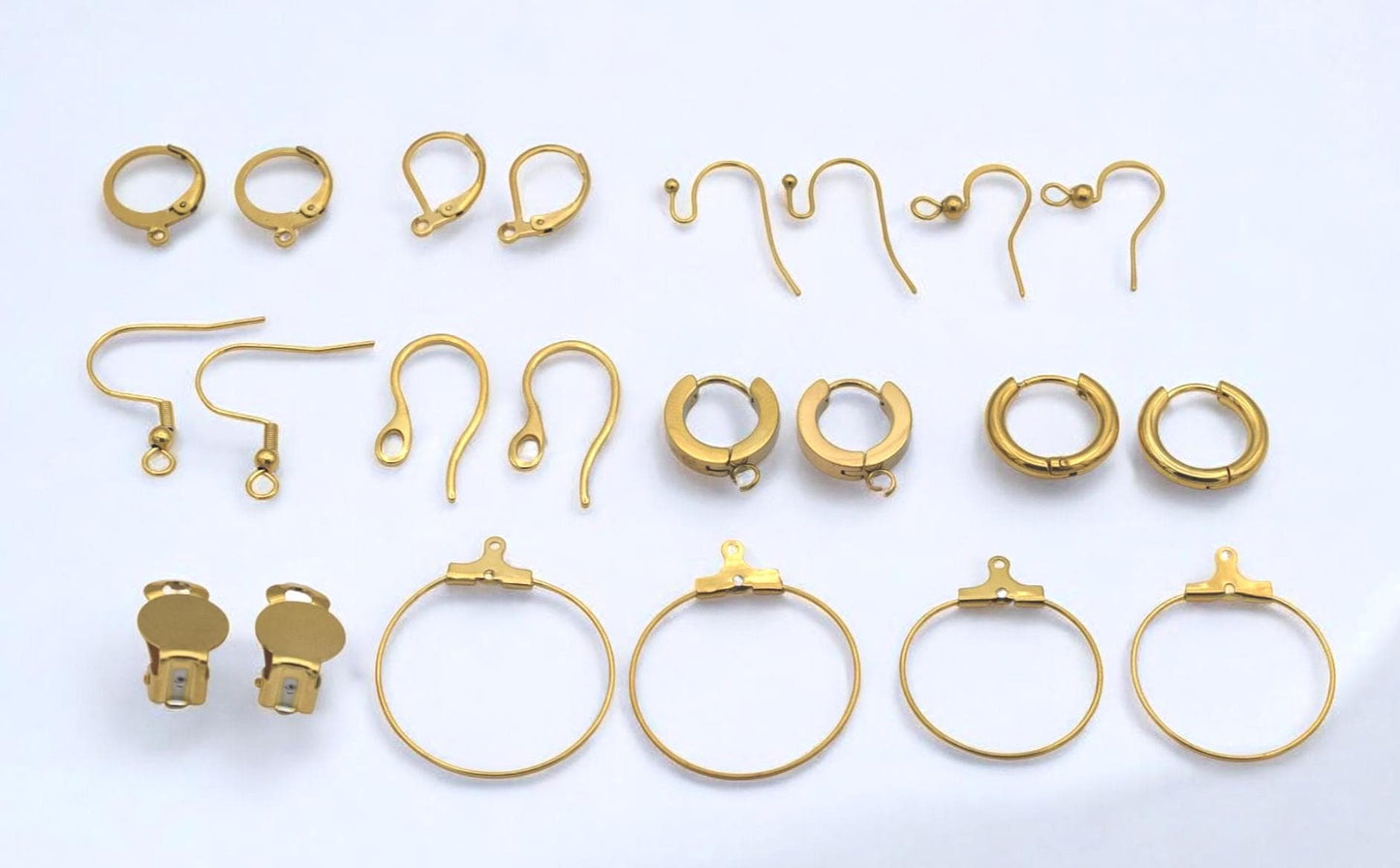 Componentes dorados para aretes incluyendo aros, ganchos y clips mostrados juntos.
Mixed gold earring components including hoops, hooks, and clips shown together.