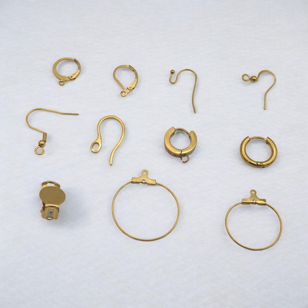 Componentes dorados para aretes decorados con flores de cerezo y cuentas doradas.
Assorted gold earring findings styled with cherry blossoms and golden beads.