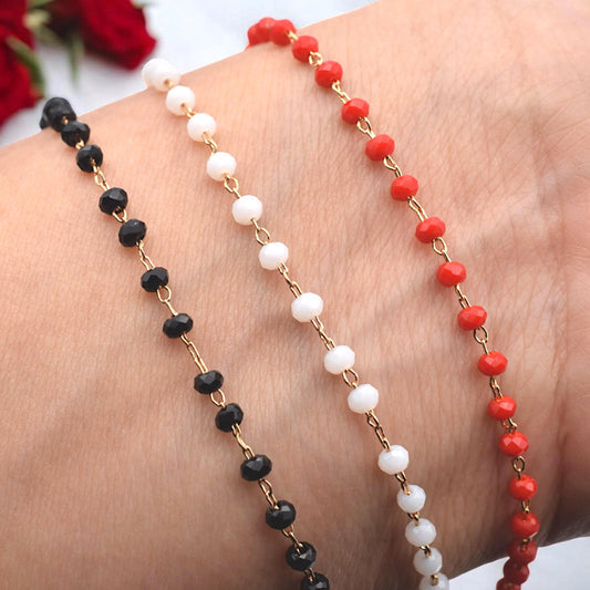 Gold rosary chain with small faceted black crystal beads shown on a white background.
Cadena de rosario dorada con cuentas de cristal facetado negro sobre fondo blanco.
