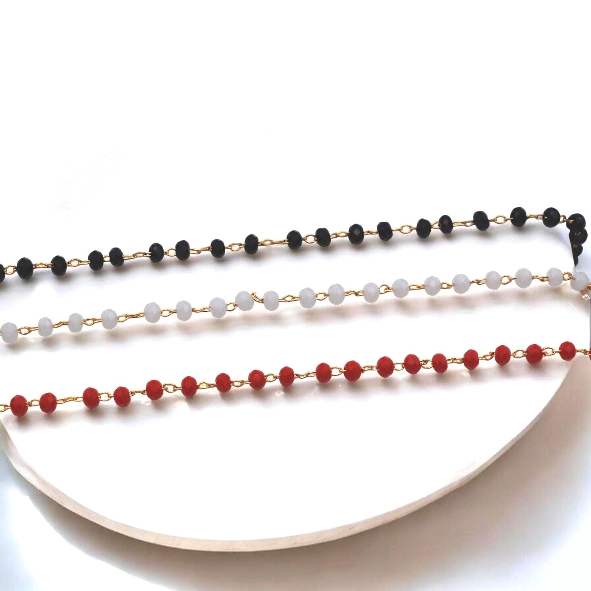 Primer plano de cadena de rosario dorada con cuentas de cristal blanco para bisutería.
Close-up of gold beaded rosary chain featuring white faceted crystal beads for jewelry making.
