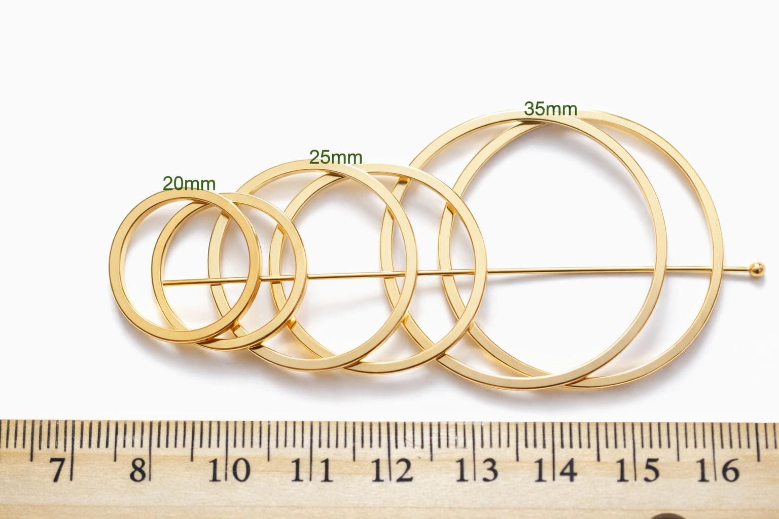 Square gold ring held by tweezers to show closed seamless construction.