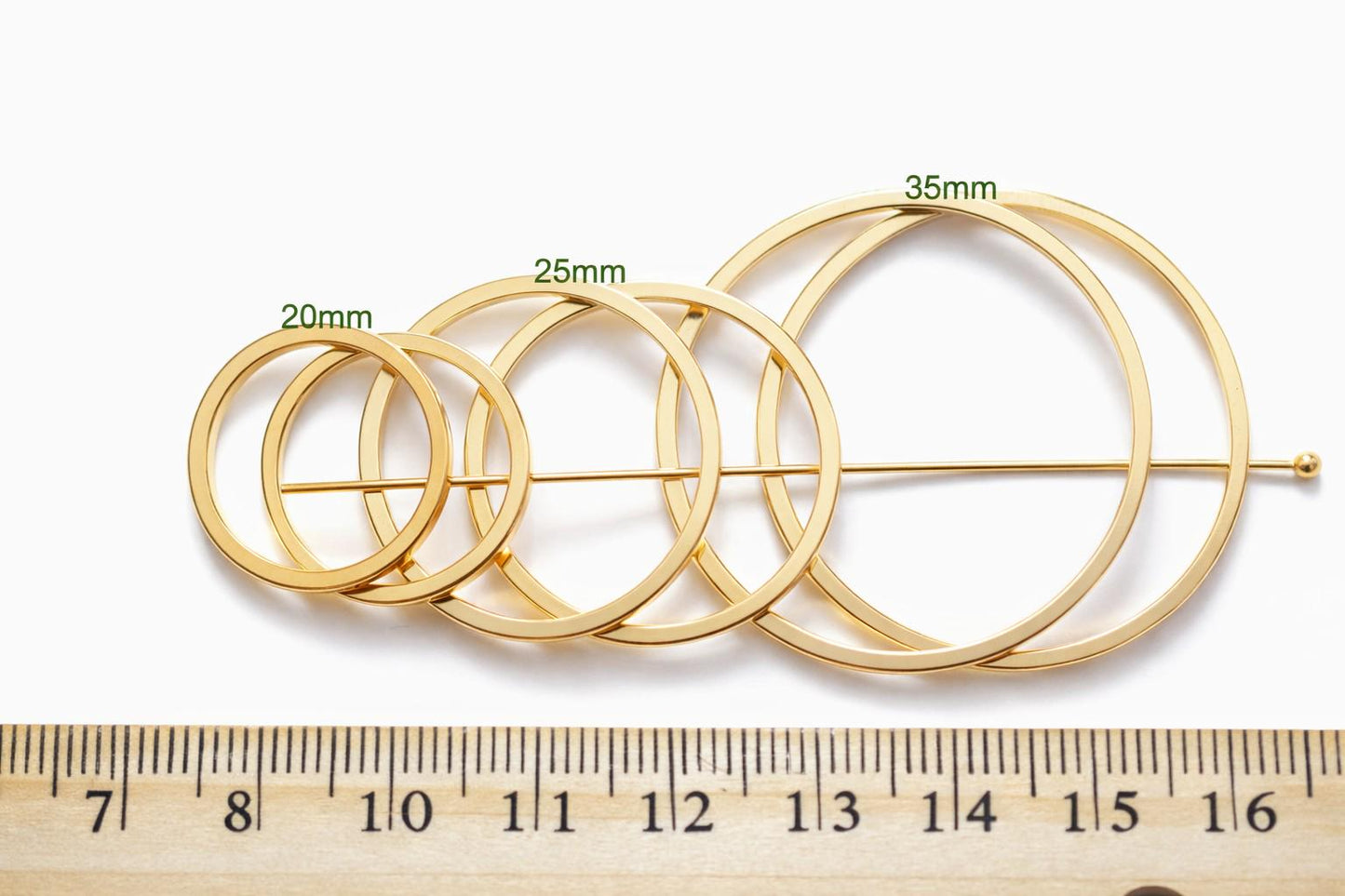 Square gold ring held by tweezers to show closed seamless construction.