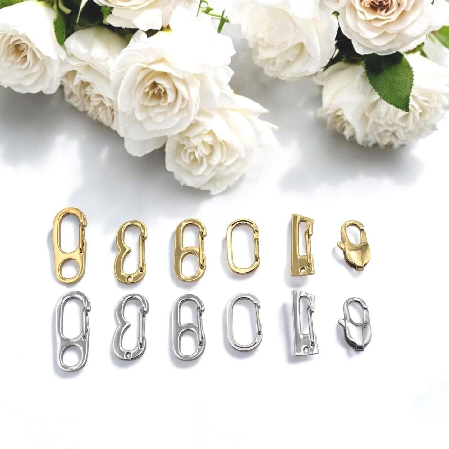 a collection of various metal clasps and keys arranged on a white background, with white roses in the background.