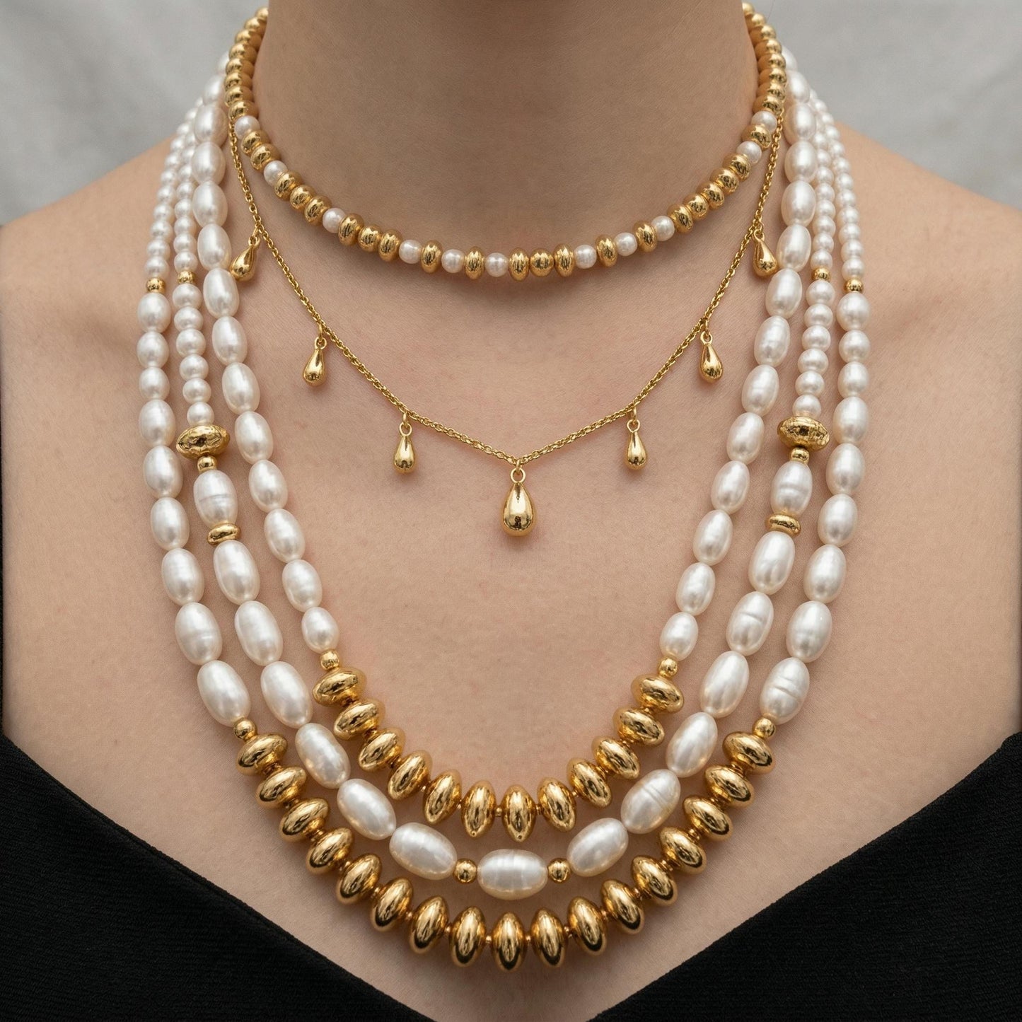 A close-up of a woman's neck adorned with a multi-strand pearl necklace, featuring a combination of white pearls and gold beads.