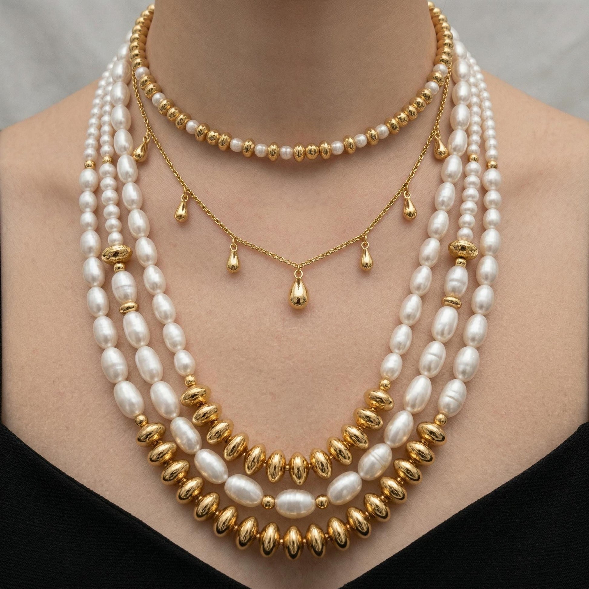 A close-up of a woman's neck adorned with a multi-strand pearl necklace, featuring a combination of white pearls and gold beads.