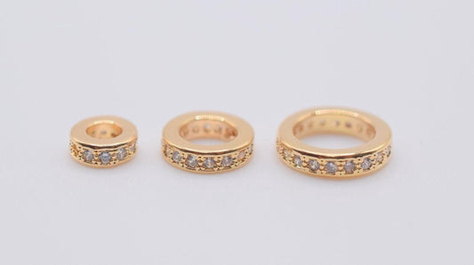 Three gold-colored rings with small diamonds set in them, arranged in a row.