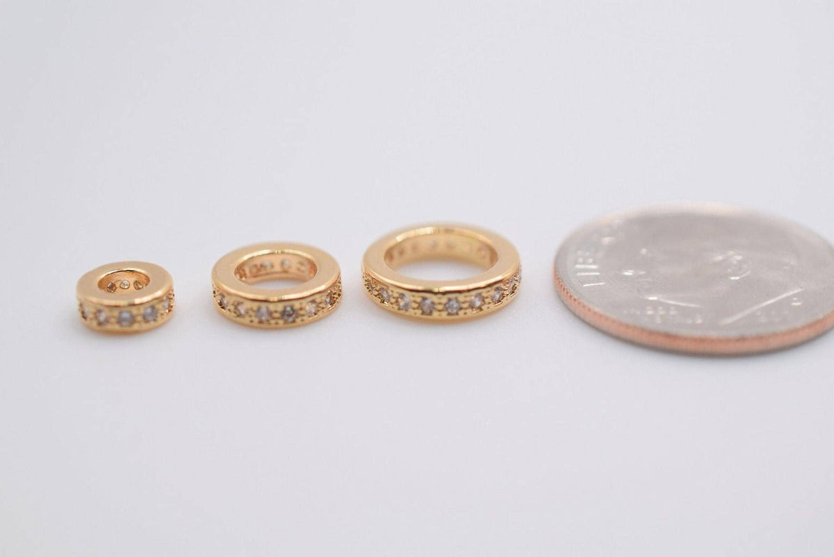 Three gold rings with small diamonds are placed next to a US quarter coin on a white background.