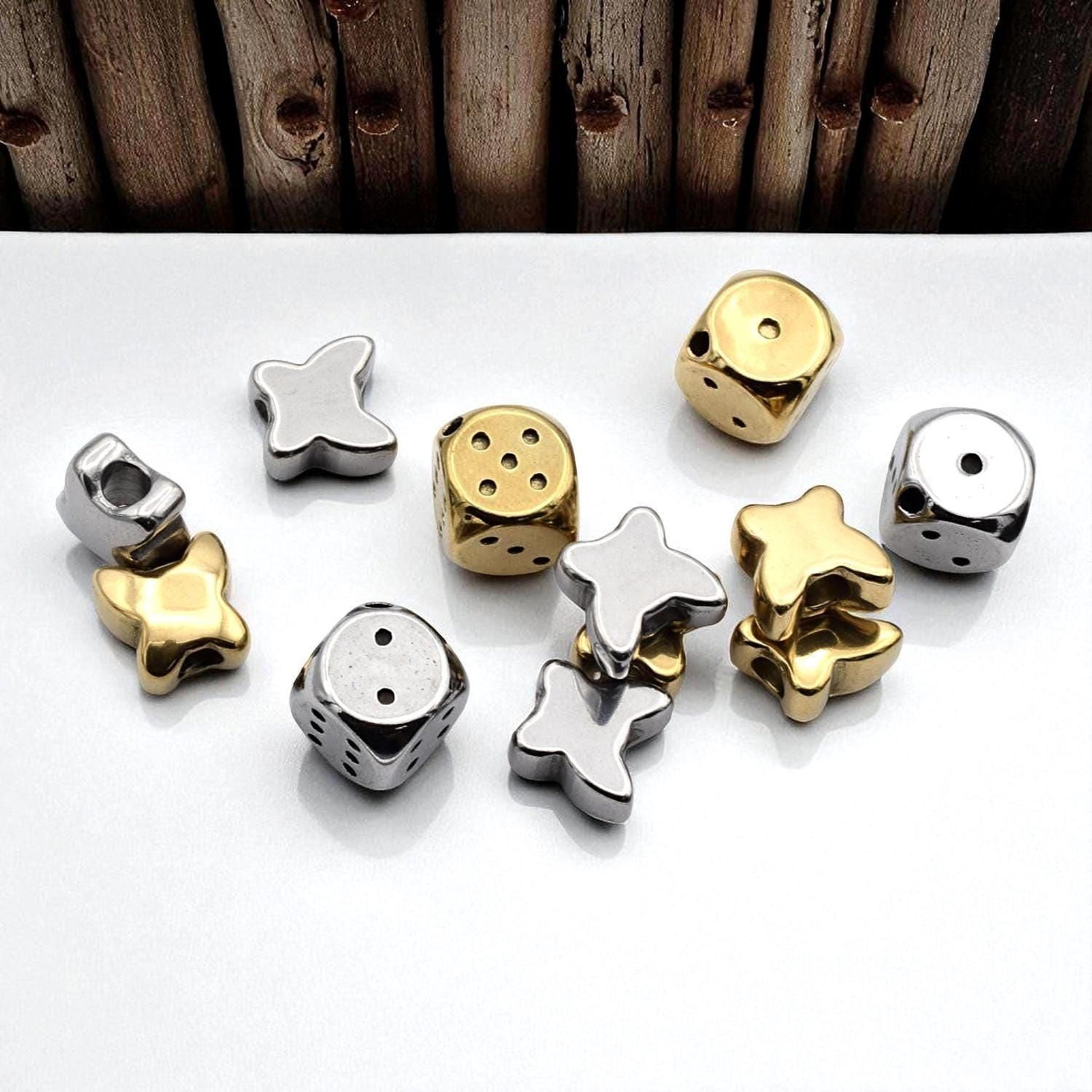 a collection of various metallic dice and beads arranged on a white surface.