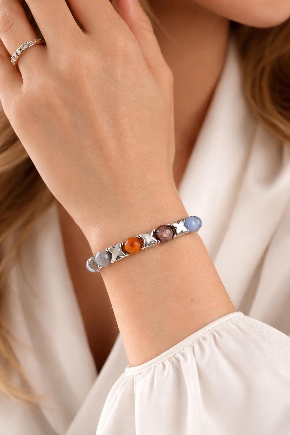 A close-up of a person's hand wearing a bracelet with colorful stones.