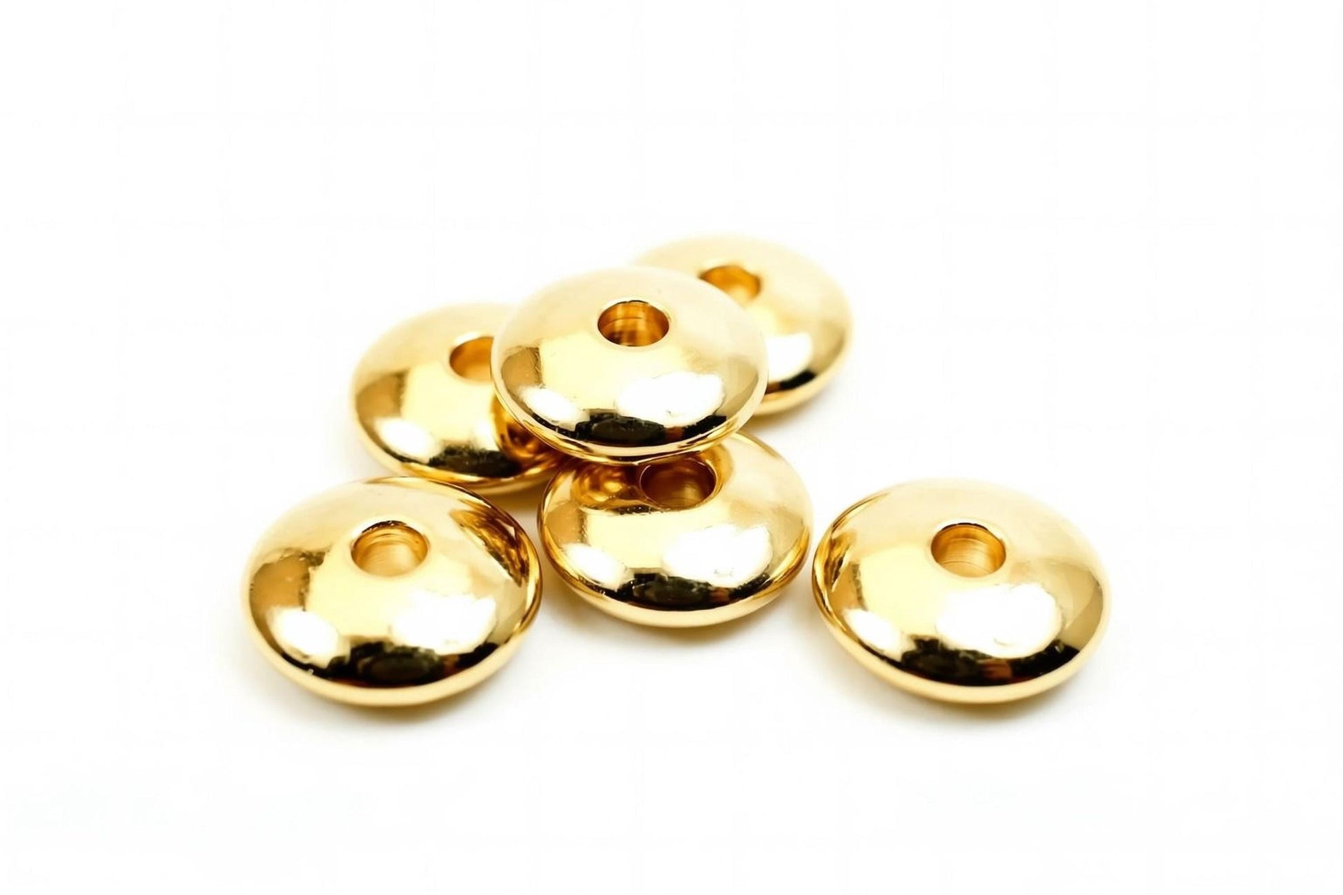 A group of shiny, golden-colored beads or buttons arranged on a white background.