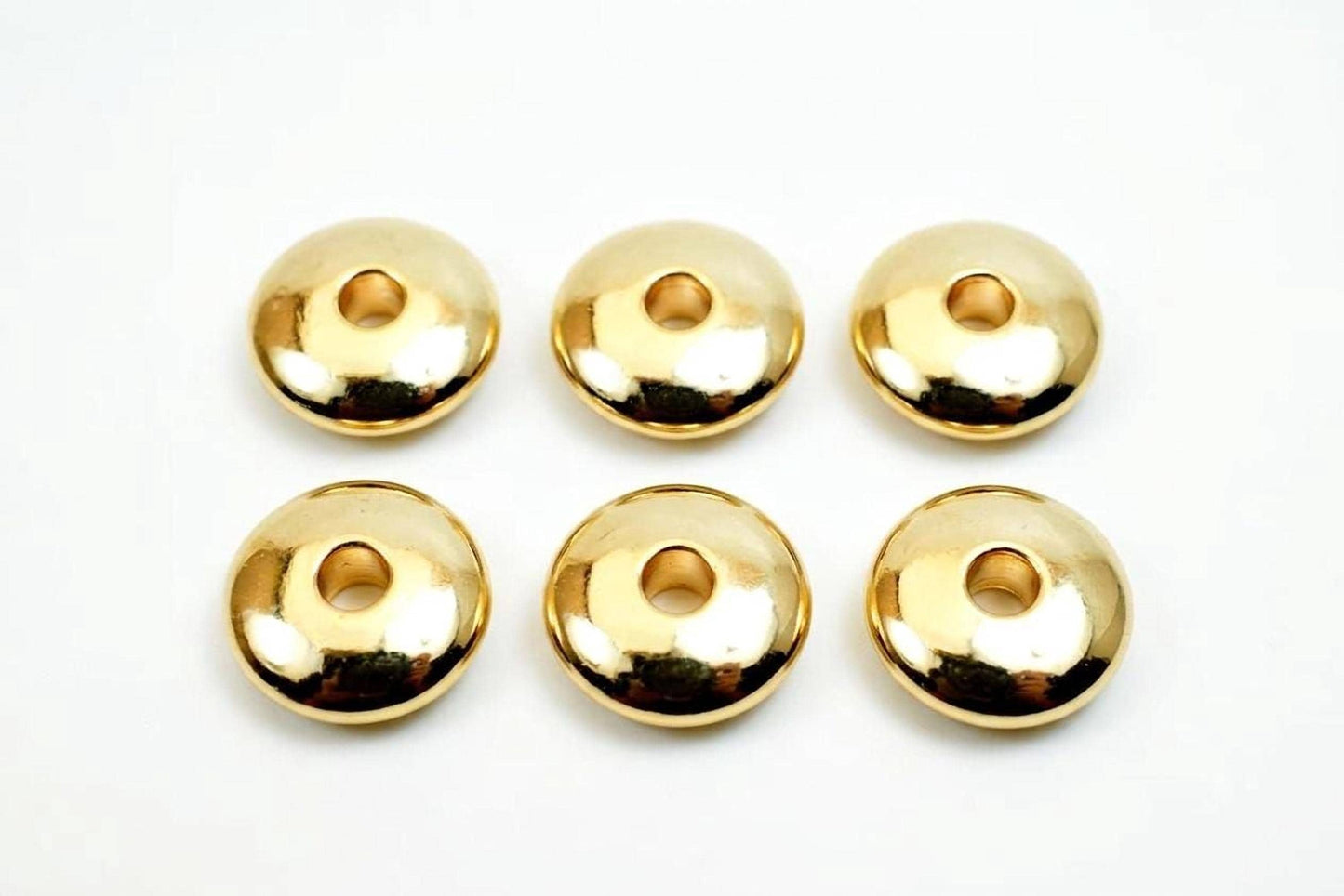 Six shiny gold-colored donut-shaped objects are arranged in a grid on a white background.