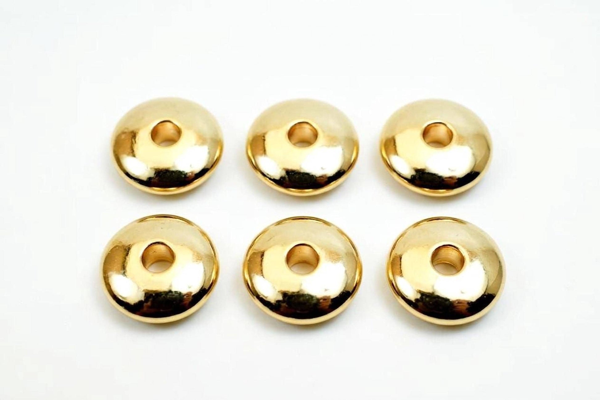 Six shiny gold-colored donut-shaped objects are arranged in a grid on a white background.