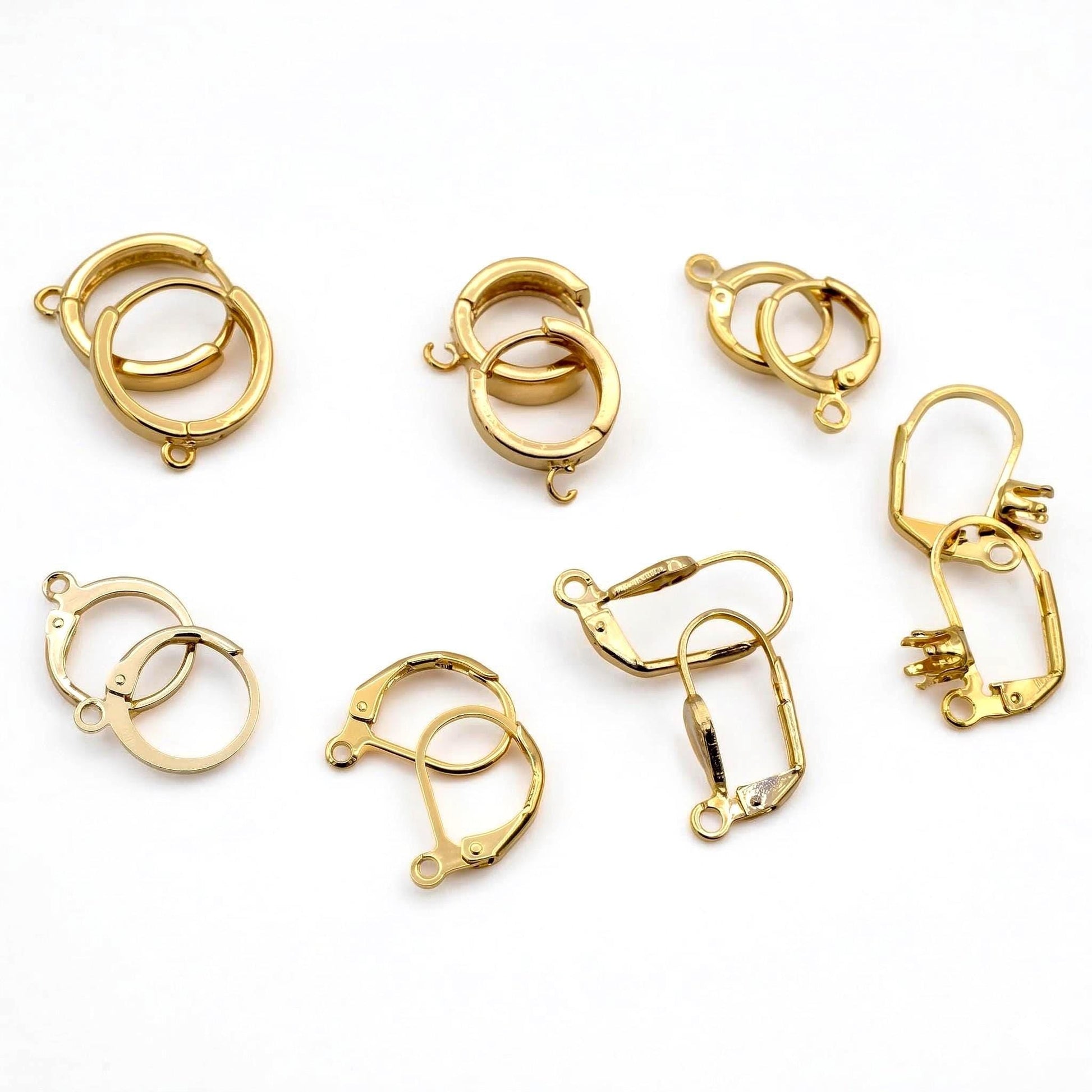 a collection of various gold-colored metal earring hooks and clasps, arranged on a white background.