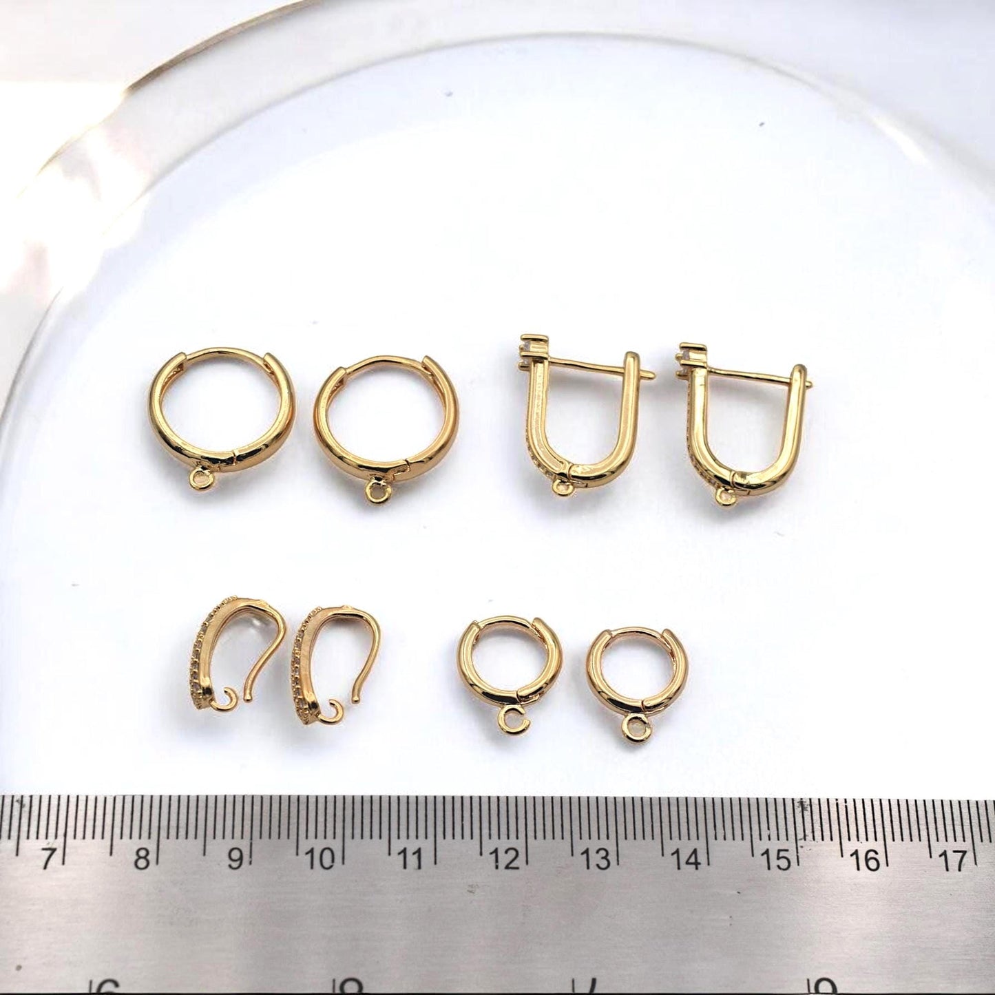 Gold hoop findings placed next to a metric ruler to show precise millimeter sizing for jewelry designers.