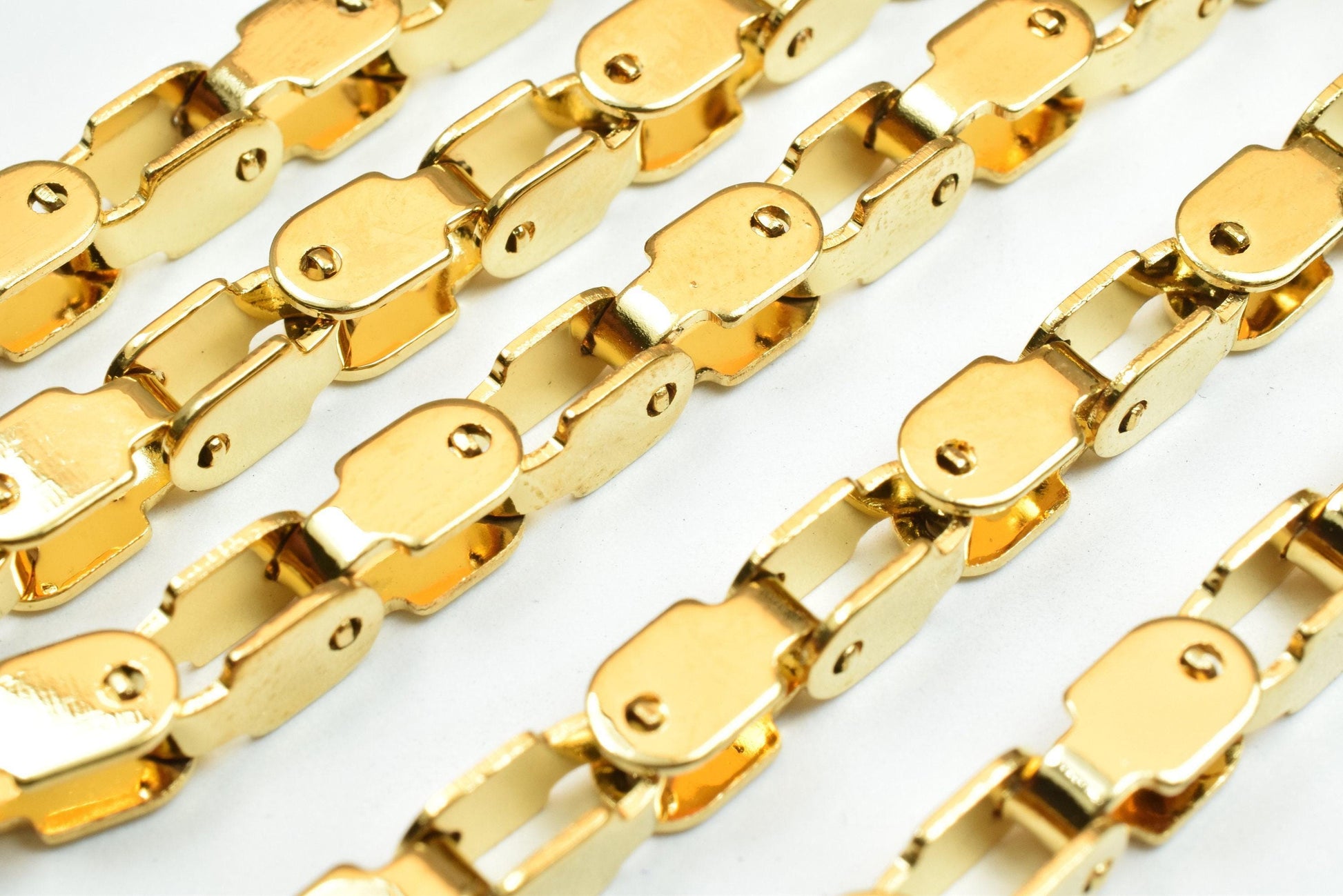 a close-up view of several gold-colored metal chains or links, arranged in a repeating pattern.