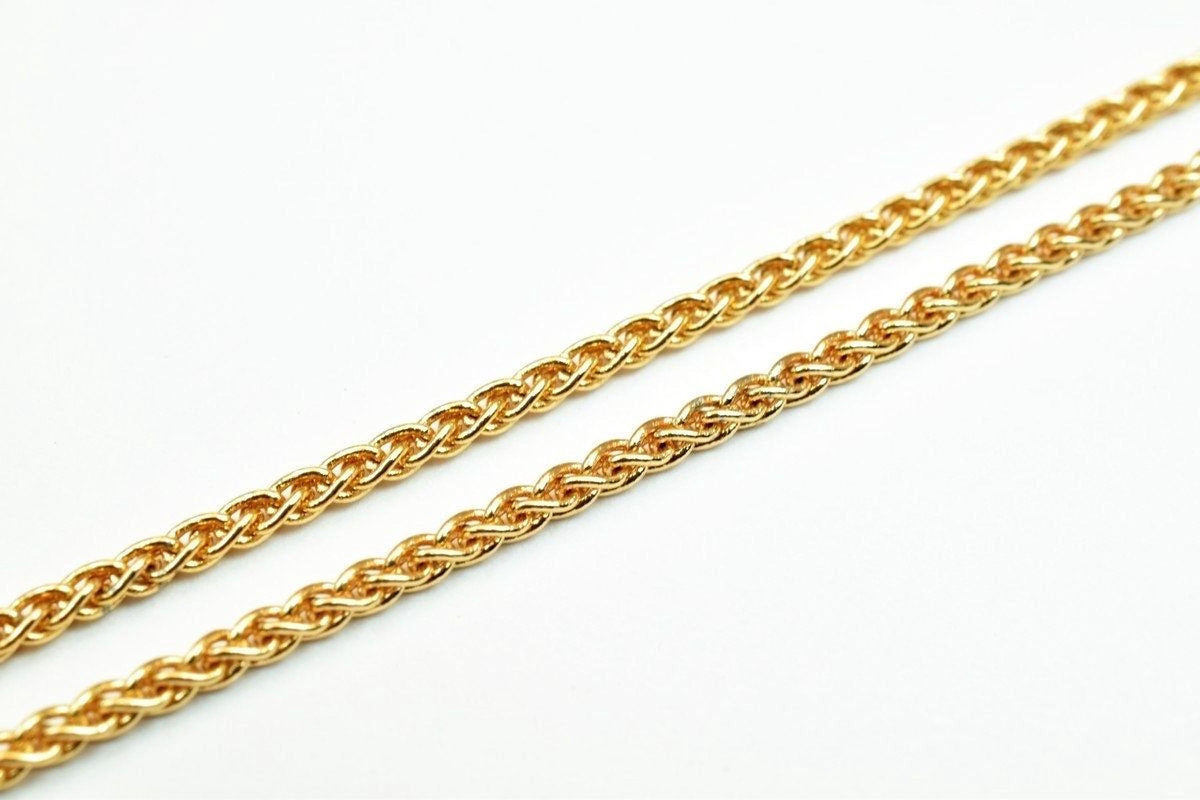 A close-up image of a gold chain necklace against a white background.