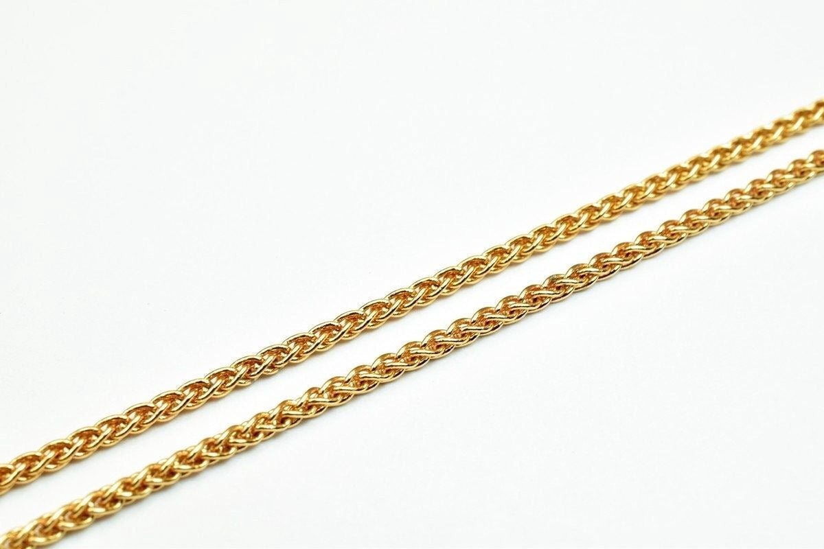 A close-up image of a gold chain necklace against a white background.