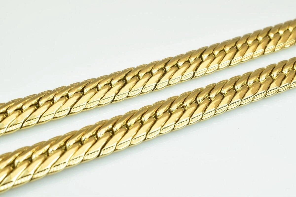 Two gold-colored metal chains with interlocking links are shown against a white background.