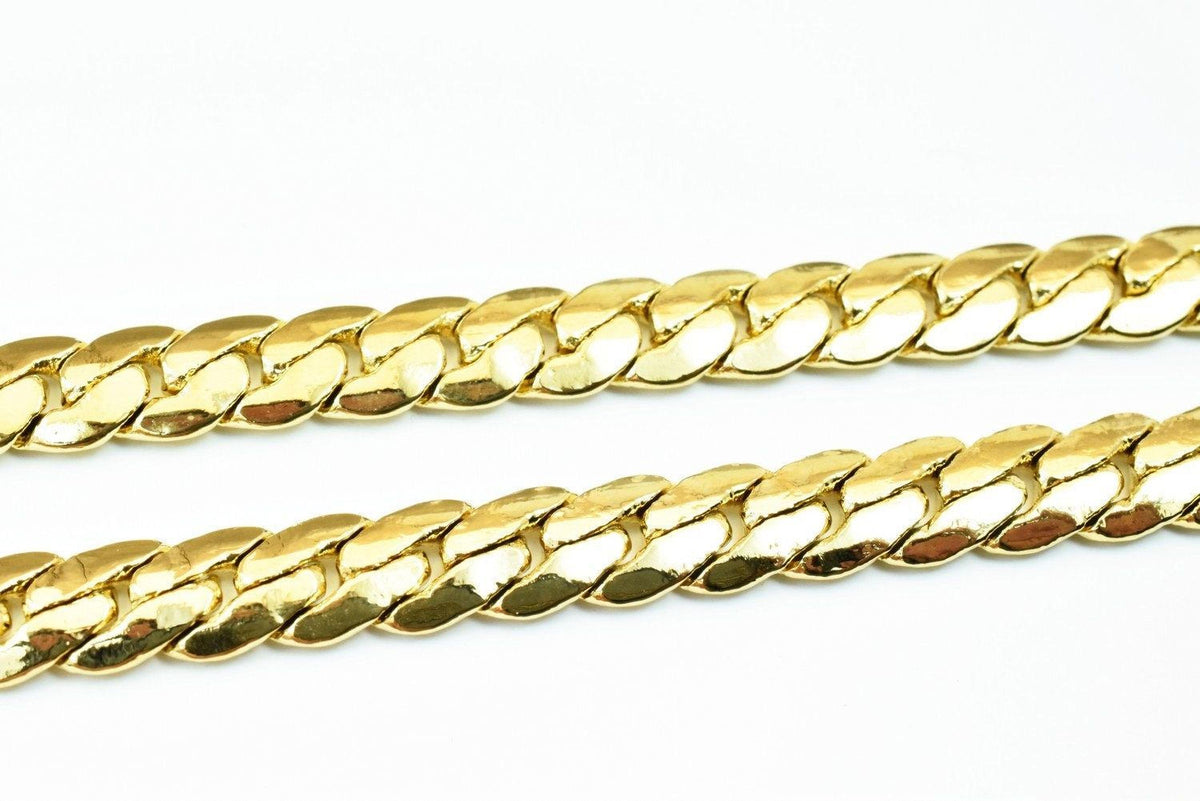 A close-up image of a gold chain necklace against a white background.