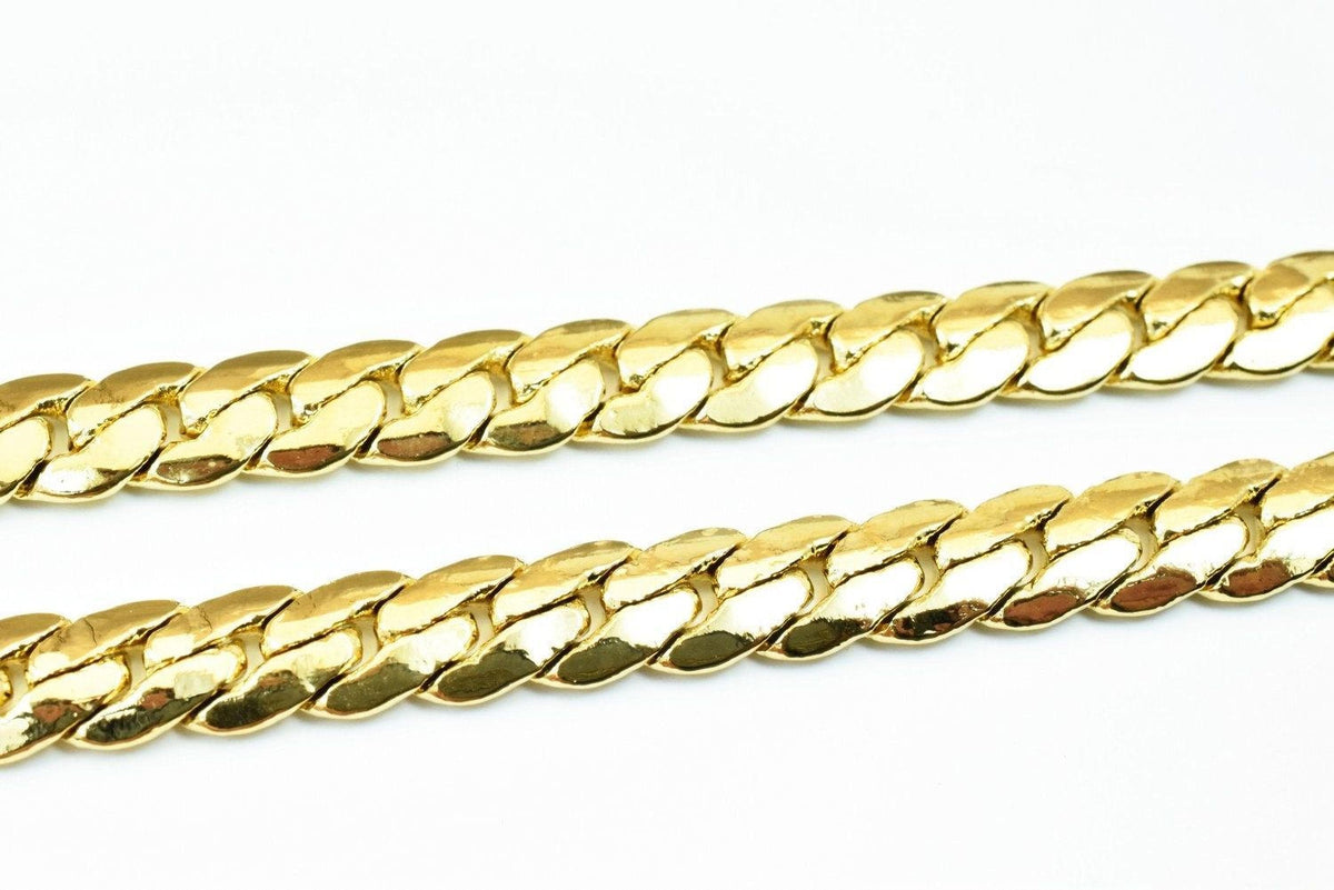 A close-up image of a gold chain necklace against a white background.