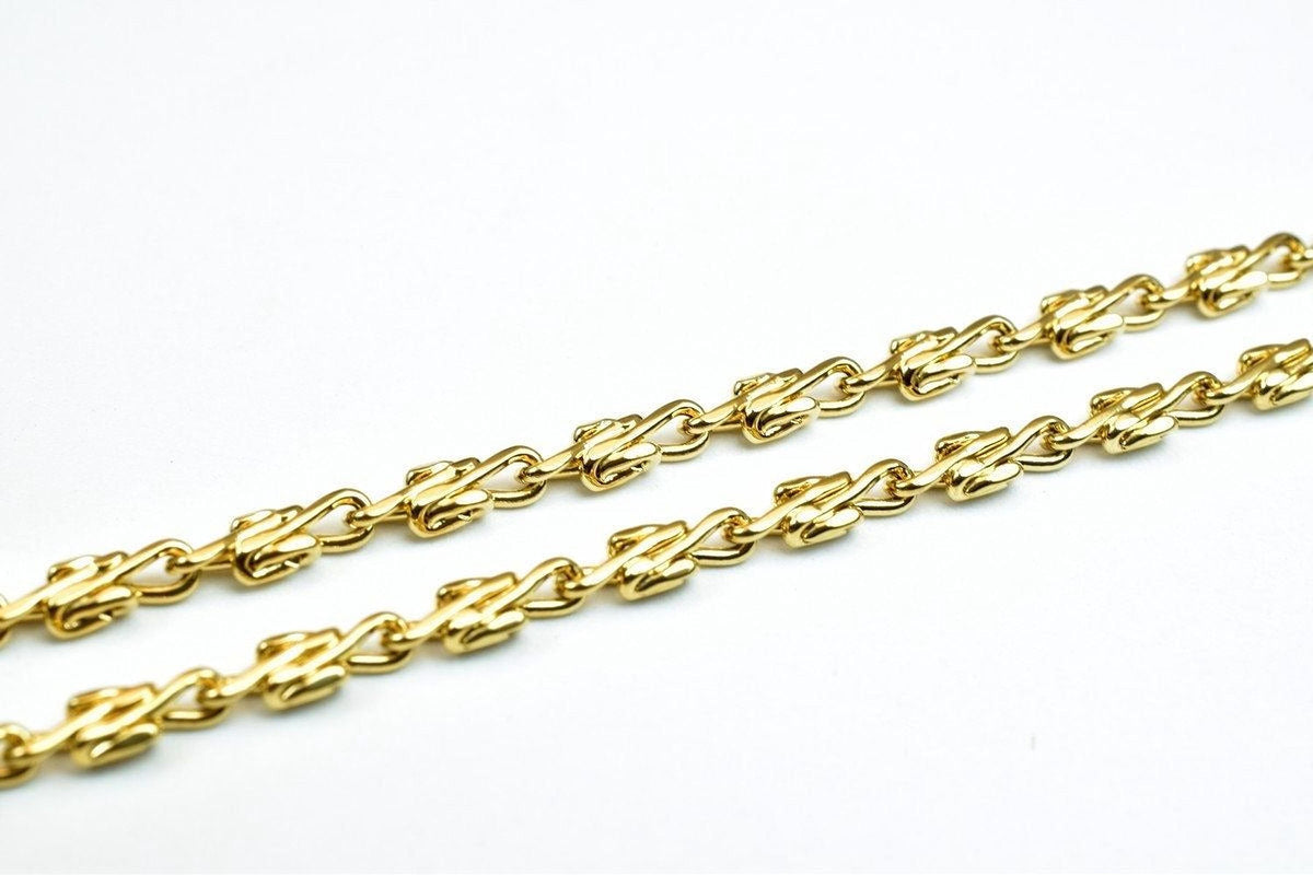 A close-up image of a gold chain with interlocking links, showcasing the intricate design and craftsmanship of the jewelry piece.