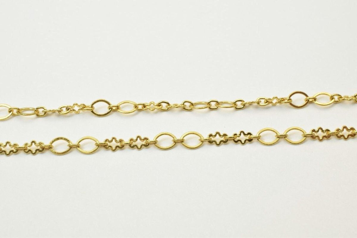 two gold-colored metal chains with various shapes and designs, including circles, stars, and floral patterns.