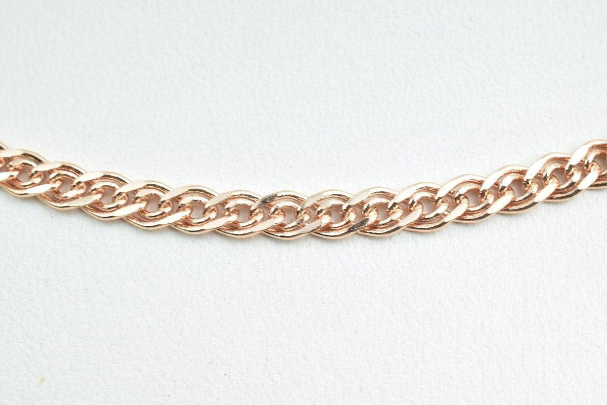A close-up view of a delicate, gold-colored chain necklace against a plain white background.
