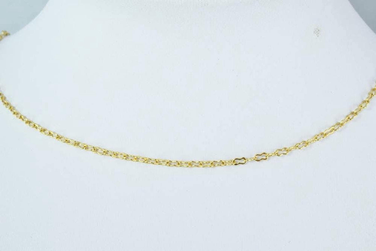 A close-up view of a gold chain necklace on a white mannequin.