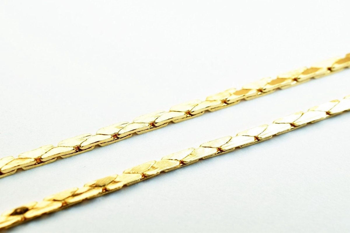 A close-up image of a gold chain necklace against a white background.