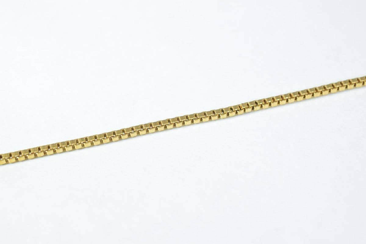A gold-colored necklace chain is shown against a white background.