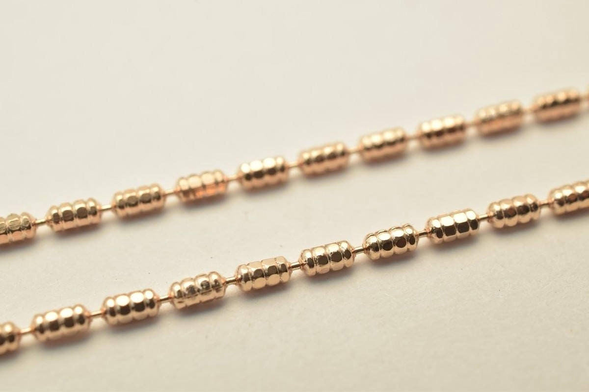 A close-up image of a gold-colored necklace with a row of small, round beads.
