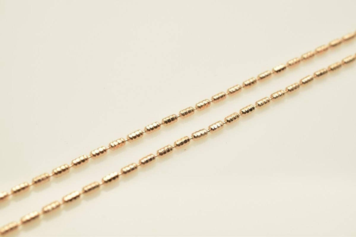A close-up image of a gold-colored necklace with multiple small, round beads arranged in a row.