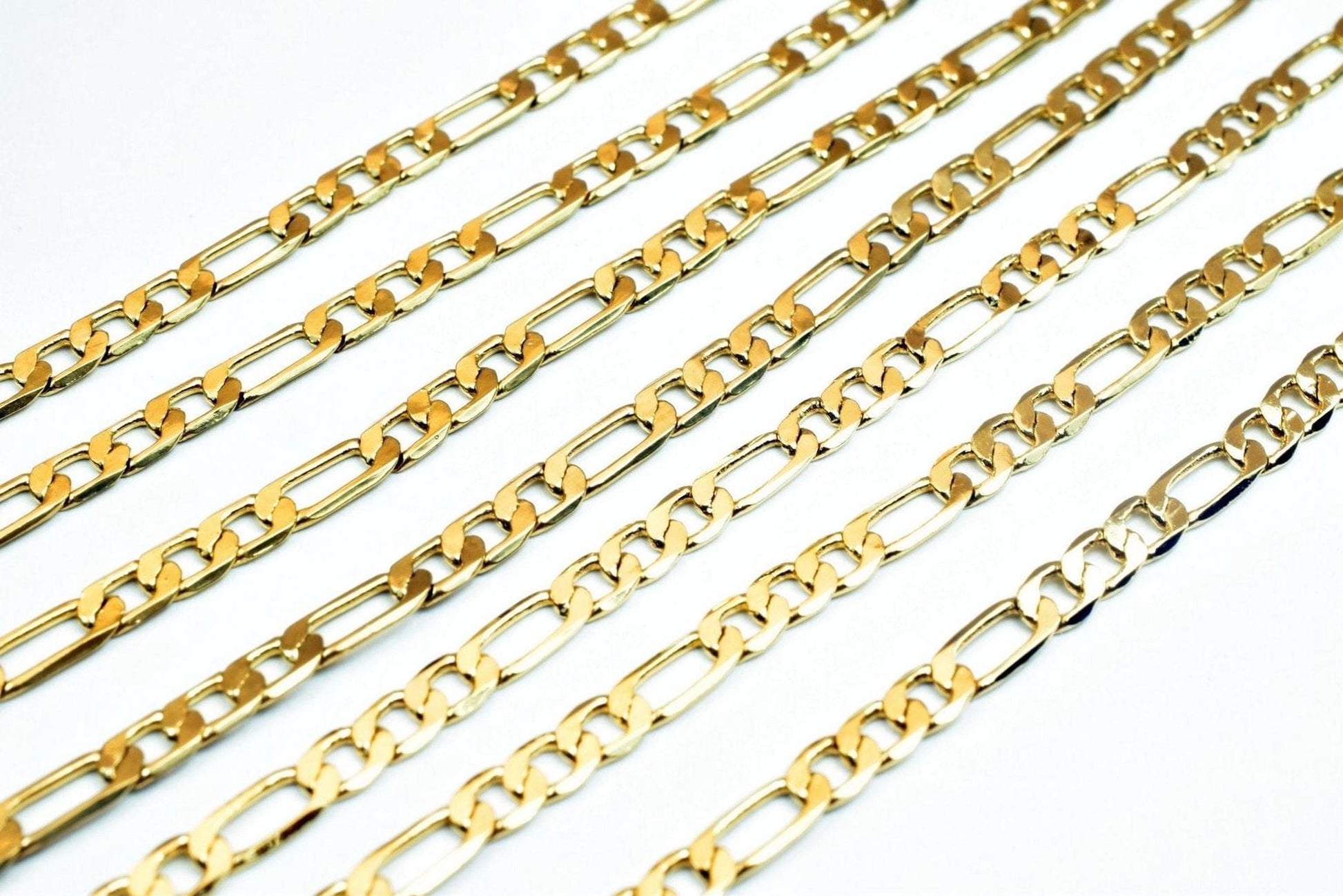 A collection of gold-colored metal chain necklaces arranged in a grid-like pattern against a white background.