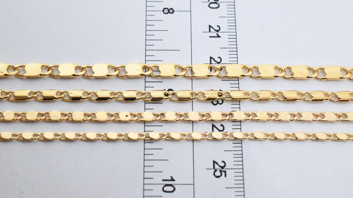 a close-up view of several gold-colored metal chains laid out on a ruler for size comparison.