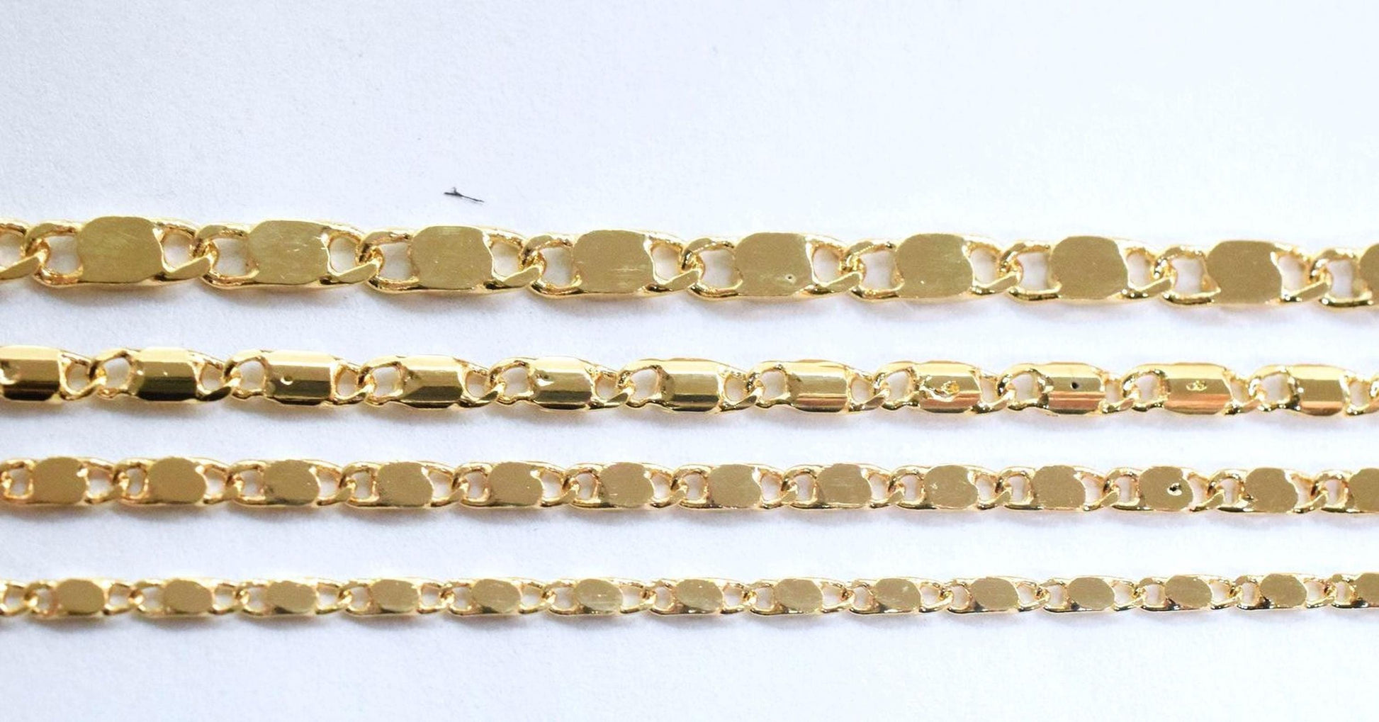 a collection of gold-colored chain links arranged in a row, with varying lengths and designs.