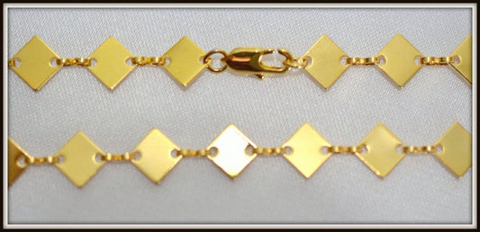 A close-up view of a gold-colored necklace with diamond-shaped links, showcasing the intricate design and craftsmanship of the piece.