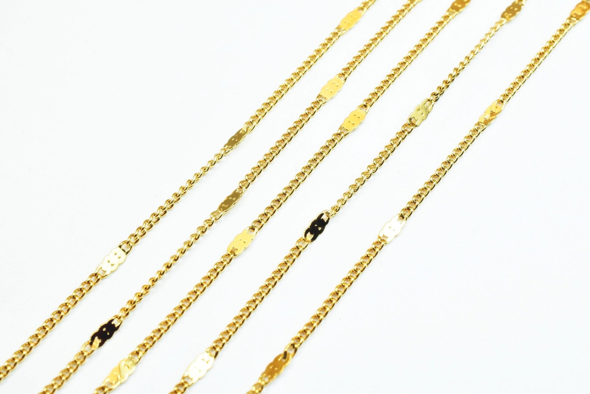 A collection of gold chain necklaces with various designs and sizes, arranged diagonally on a white background.